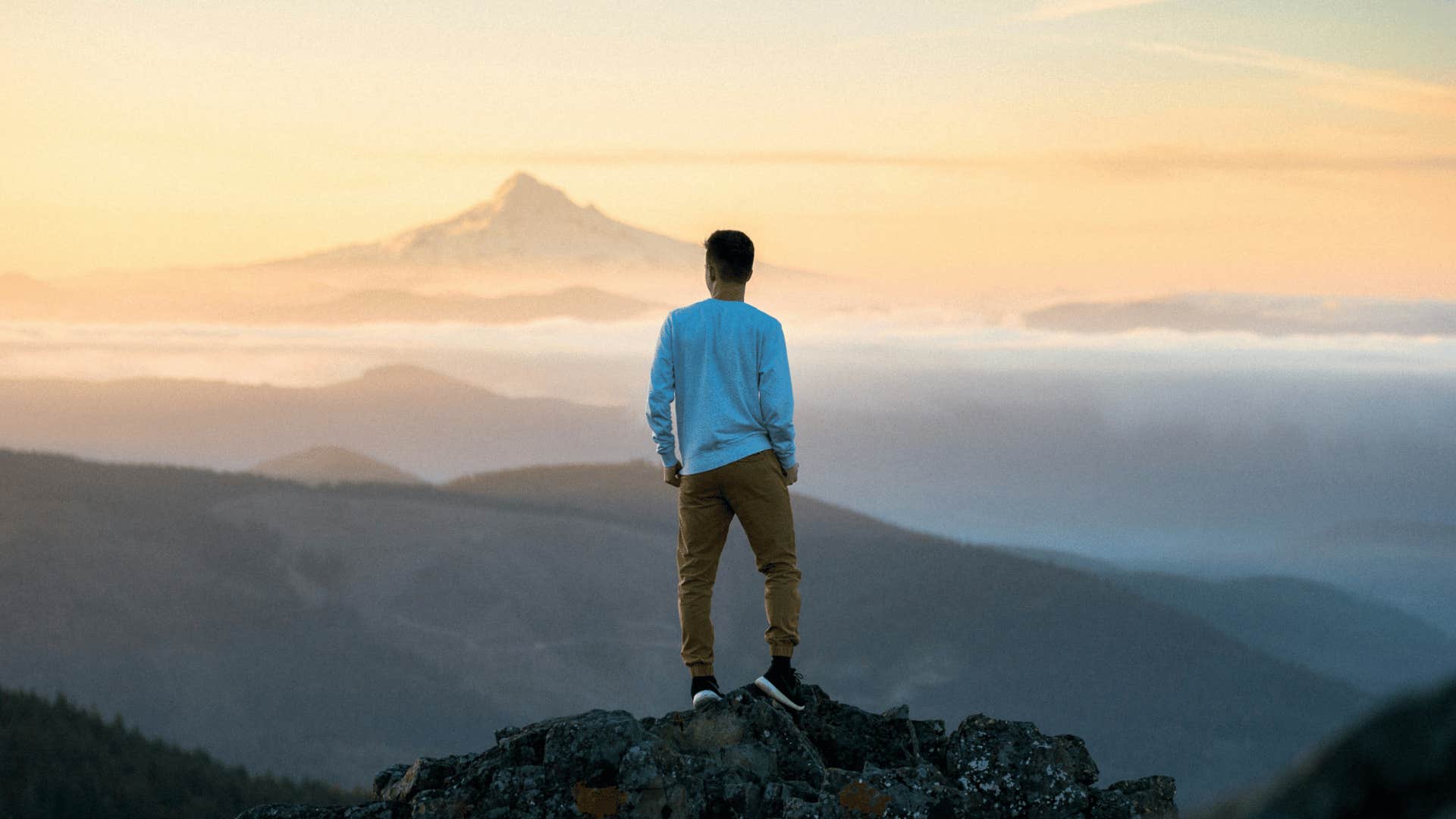 man standing tall and straight on top of a mountain