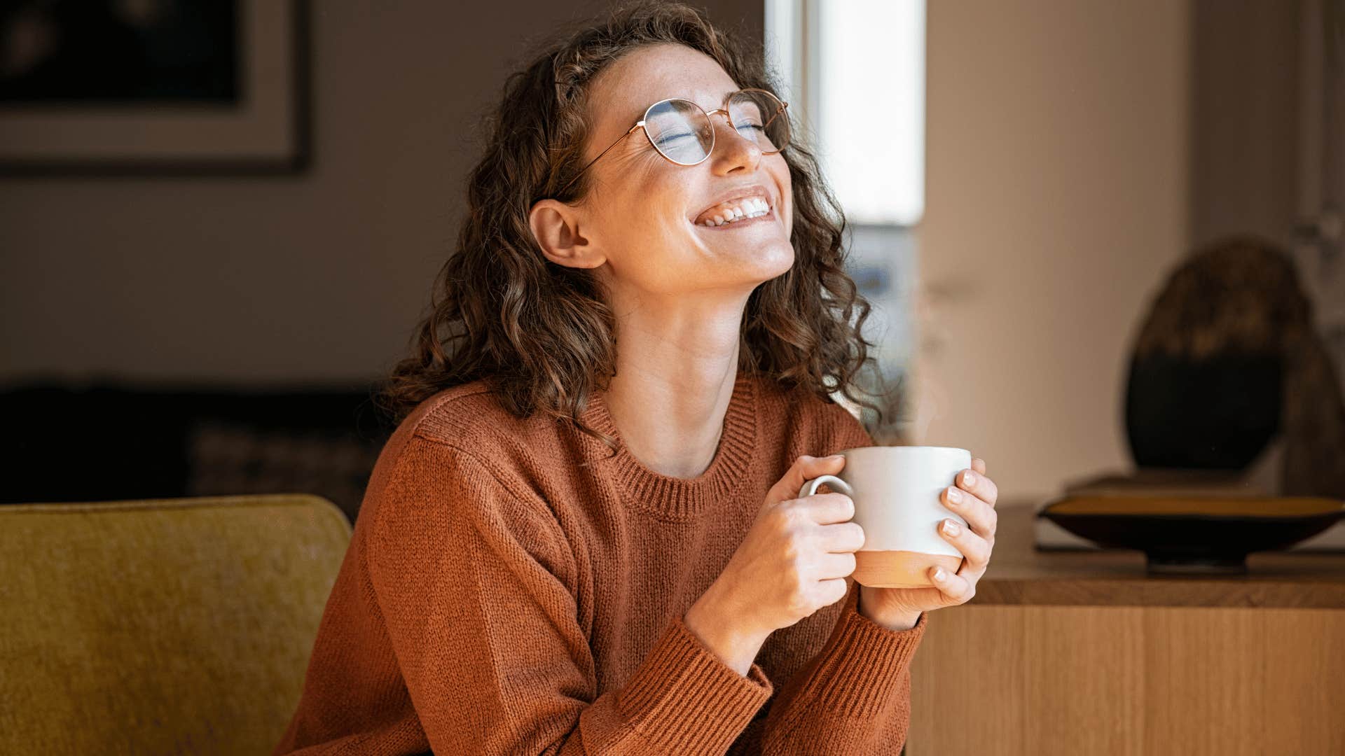 woman smiling while drinking coffee