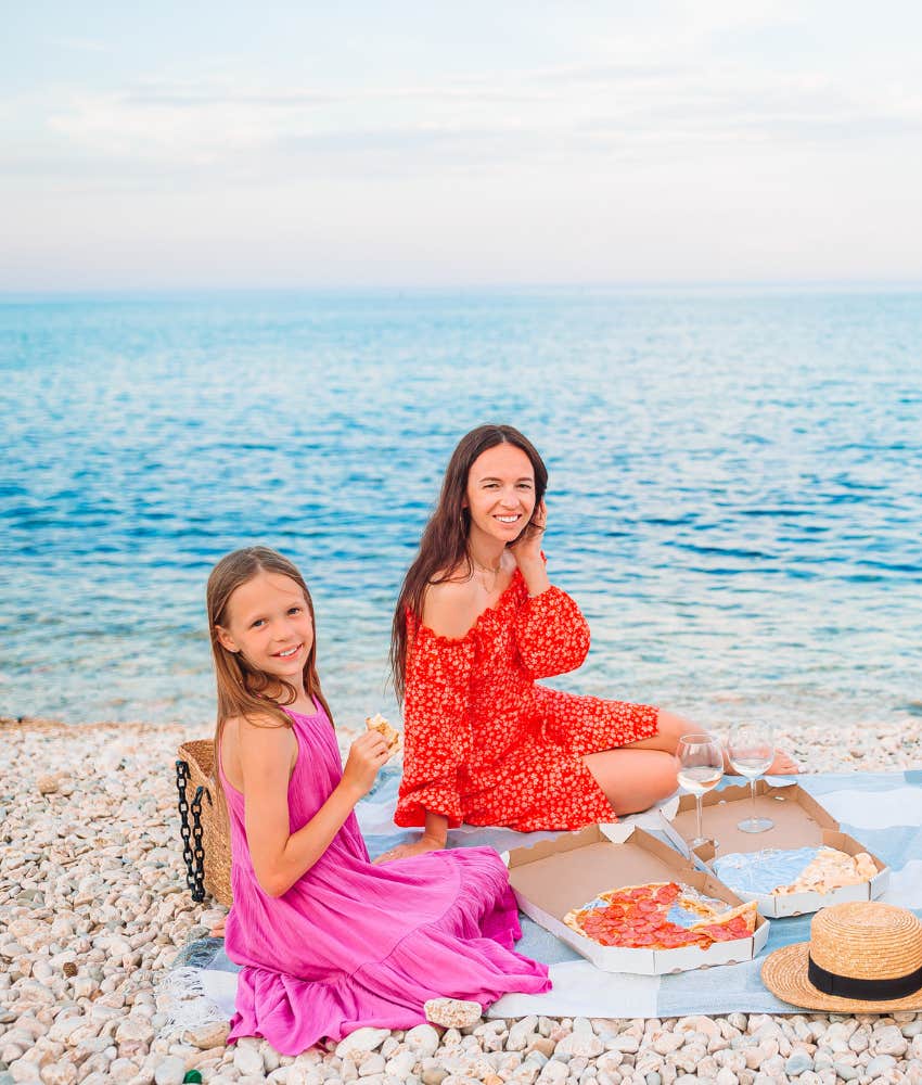 mom and daughter eating pizza lakeside