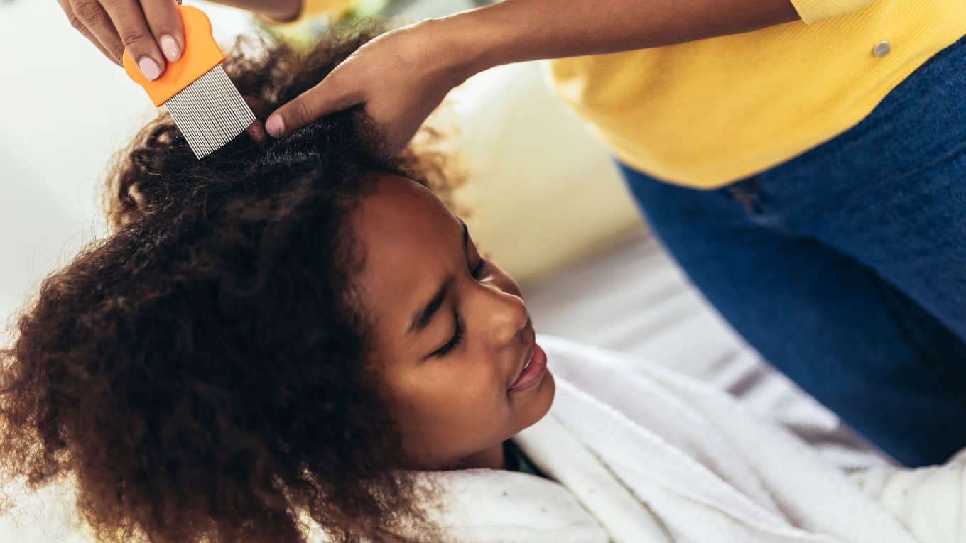 woman doing little black girl's hair