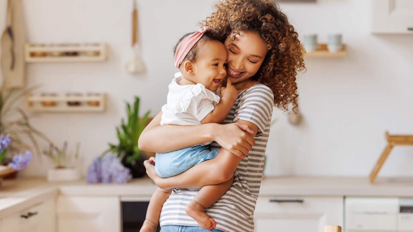 mom holding her baby daughter in the kitchen