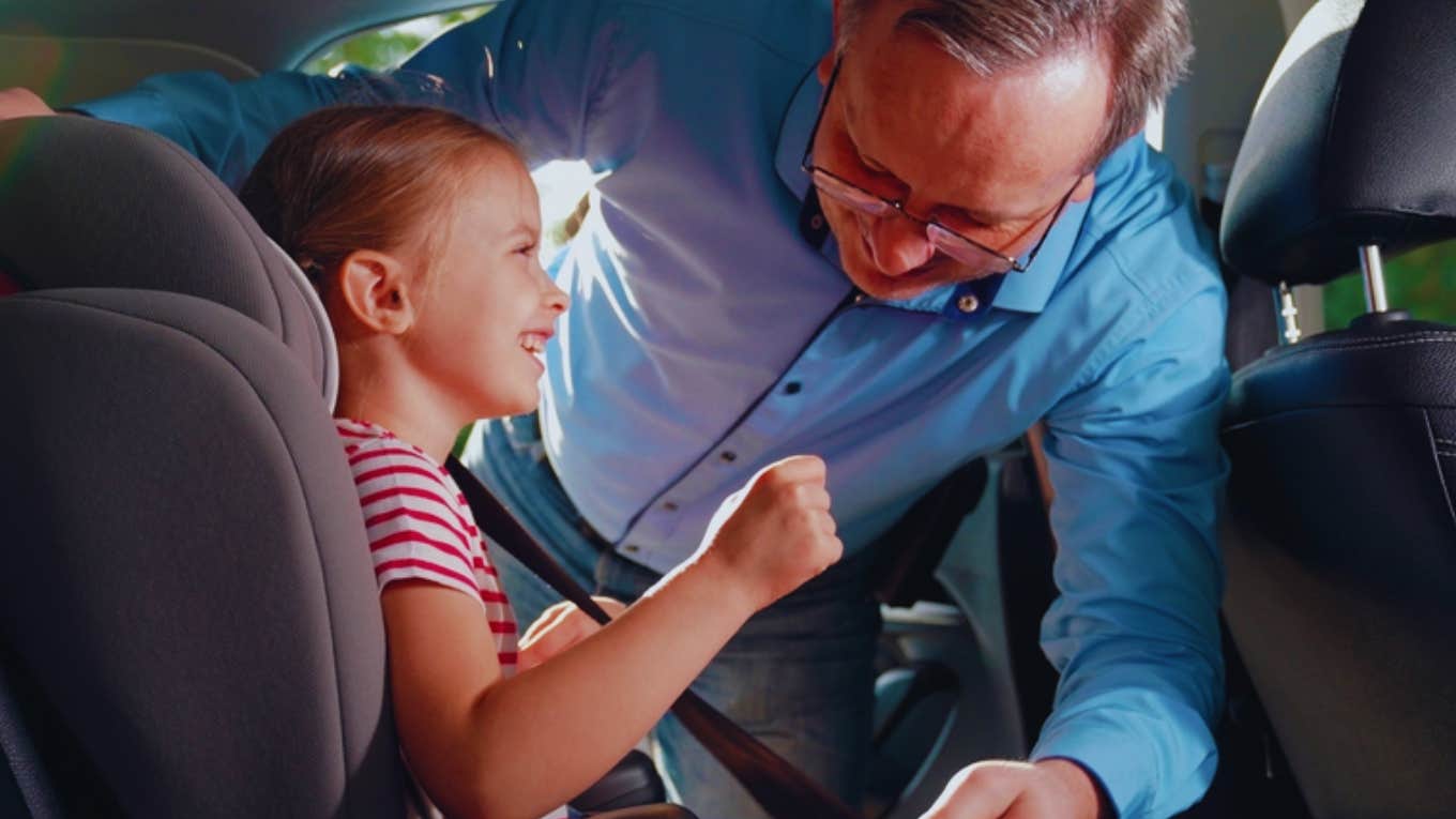 driver buckling little girl in car seat