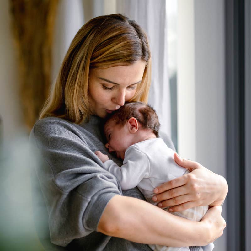 woman holding baby and kissing its head