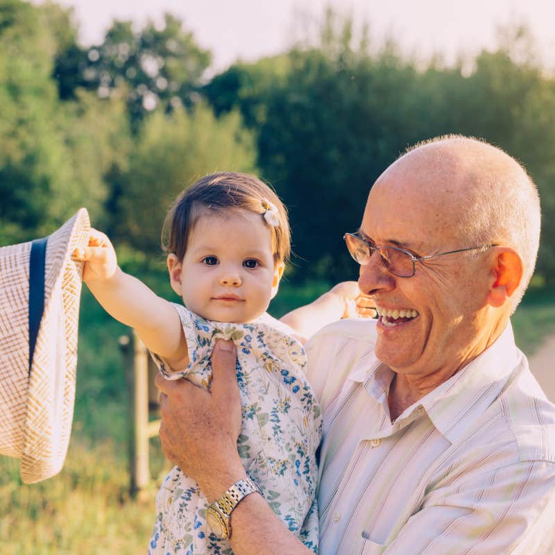 older man holding baby outside