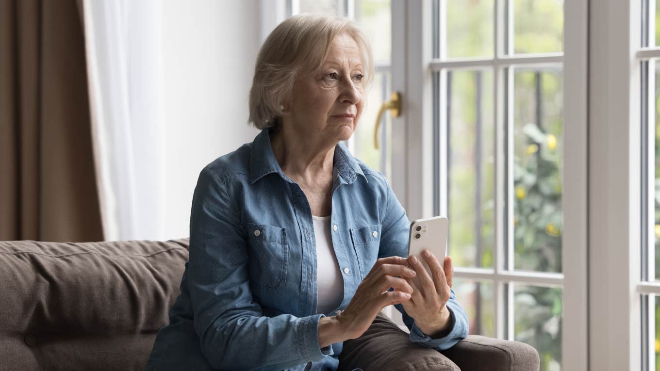 serious woman thinking while holding phone in her hands