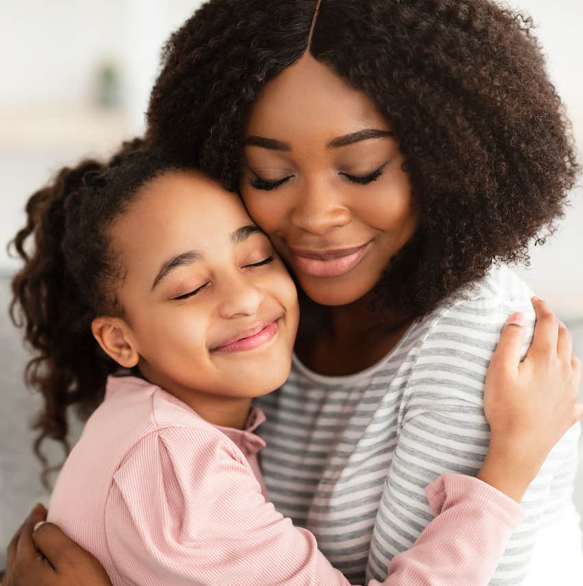 Woman hugs child, both smile