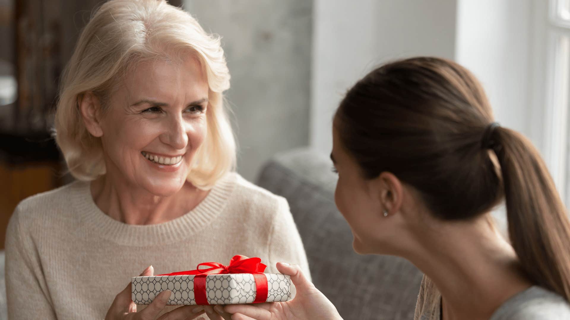 woman giving gift to adult daughter