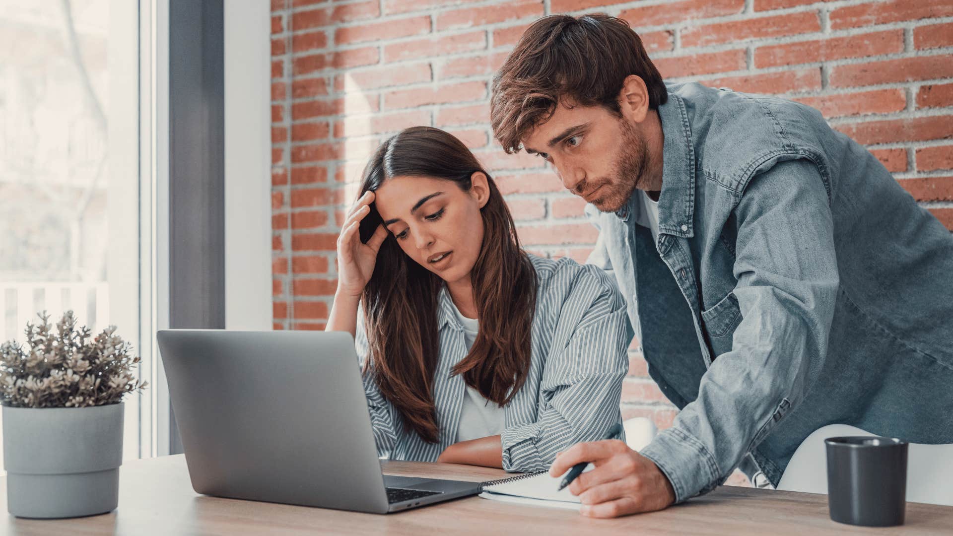 man looking at laptop with frustrated woman 