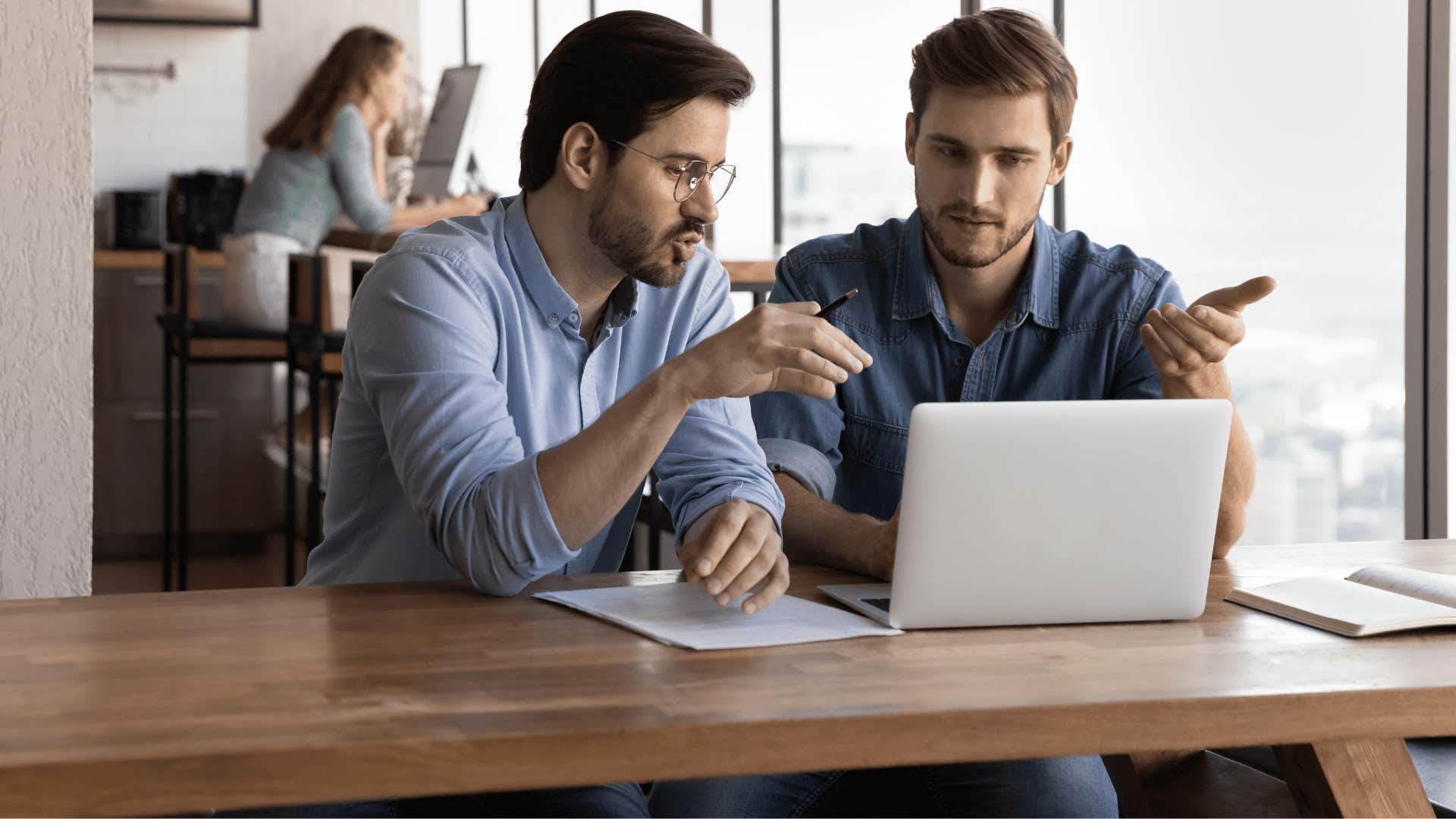 two men talking and looking at laptop