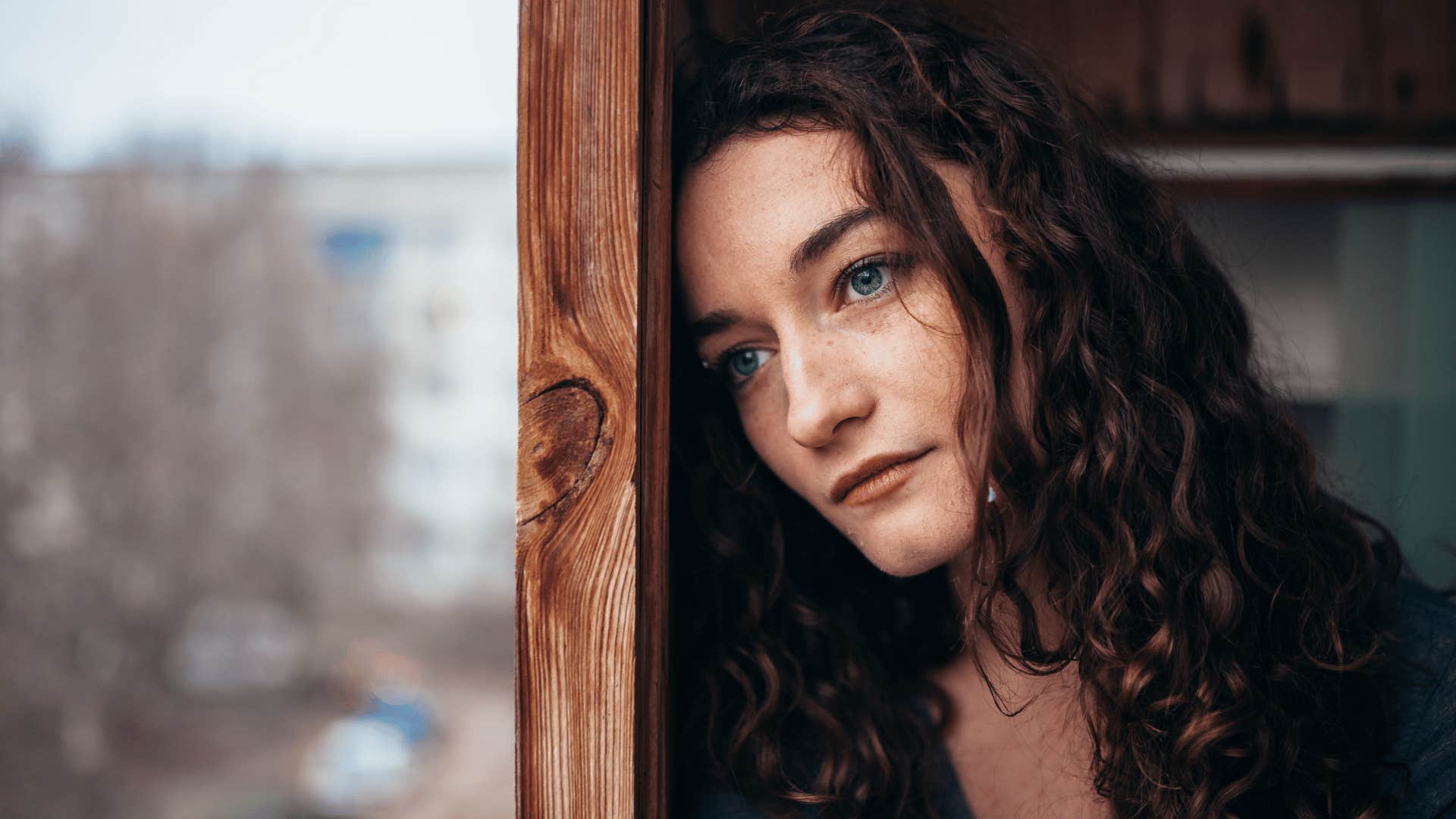 woman looking outside of window reflecting 