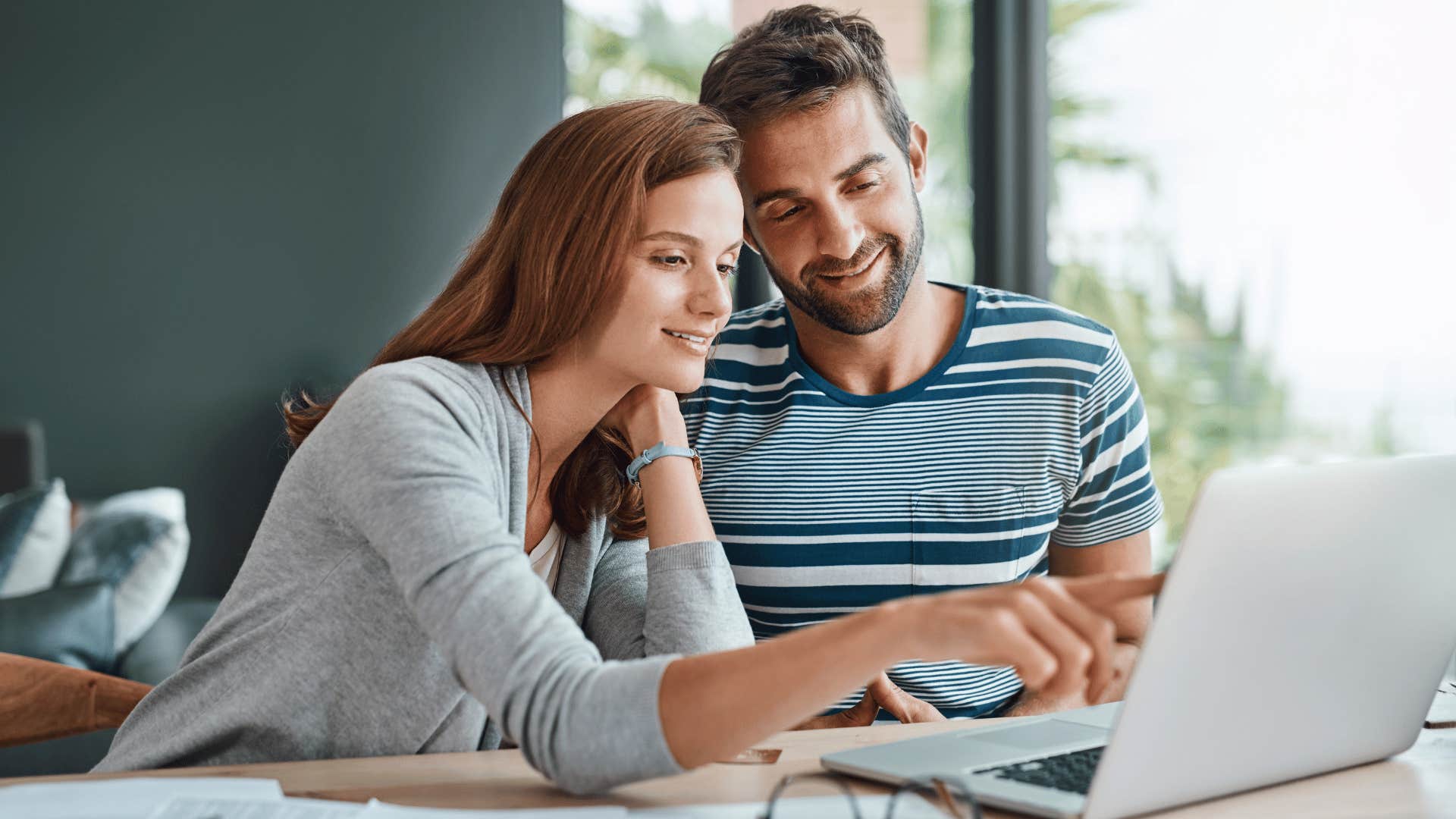 woman pointing at laptop while man smiles