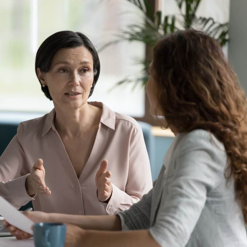 business professional woman talking to younger female colleague at office table