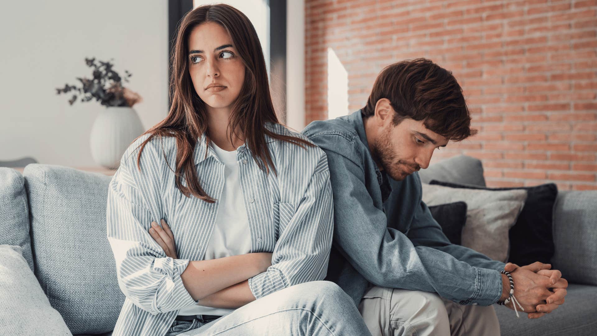 woman crossing arms looking annoyed while man looks down