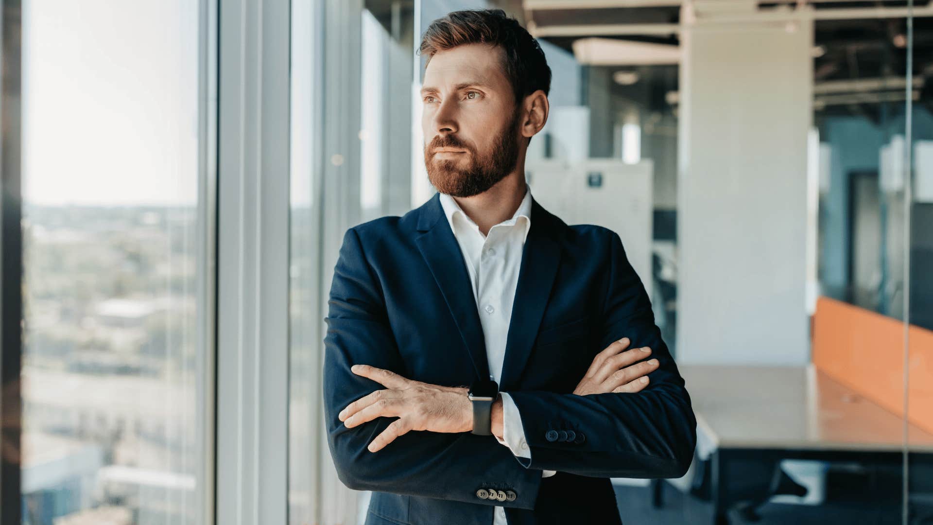 man crossing arms while looking out window 