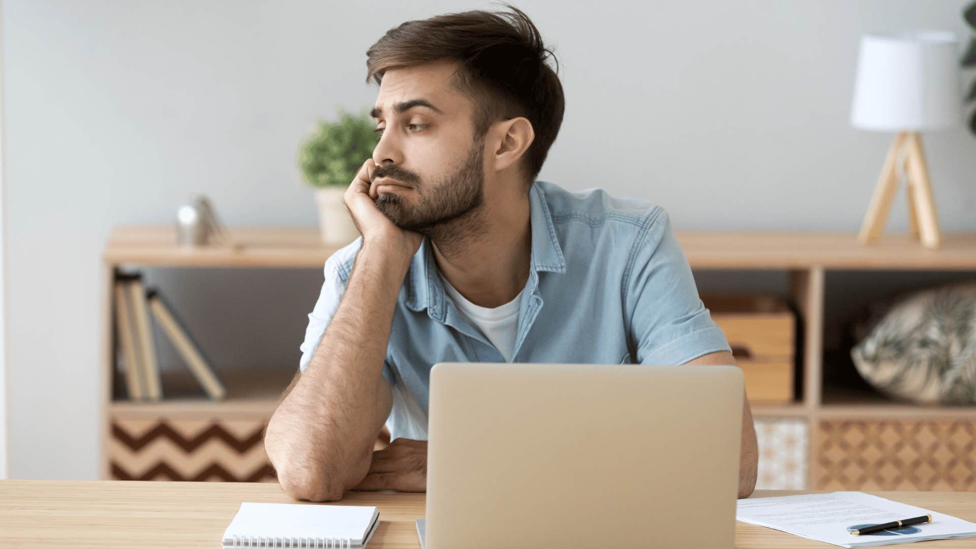 man looking unmotivated while sitting in front of laptop 