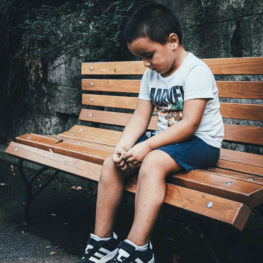 sad young boy sitting on park bench