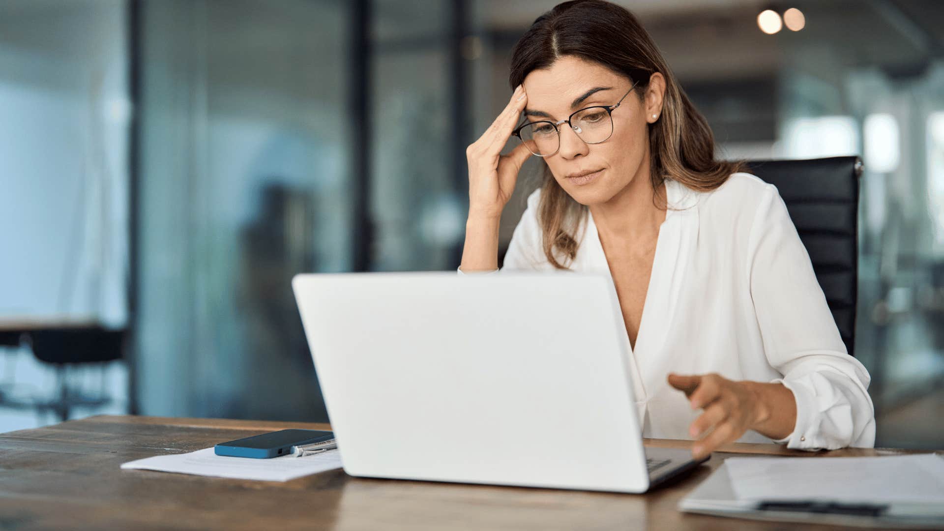 woman looking stressed while staring at laptop 