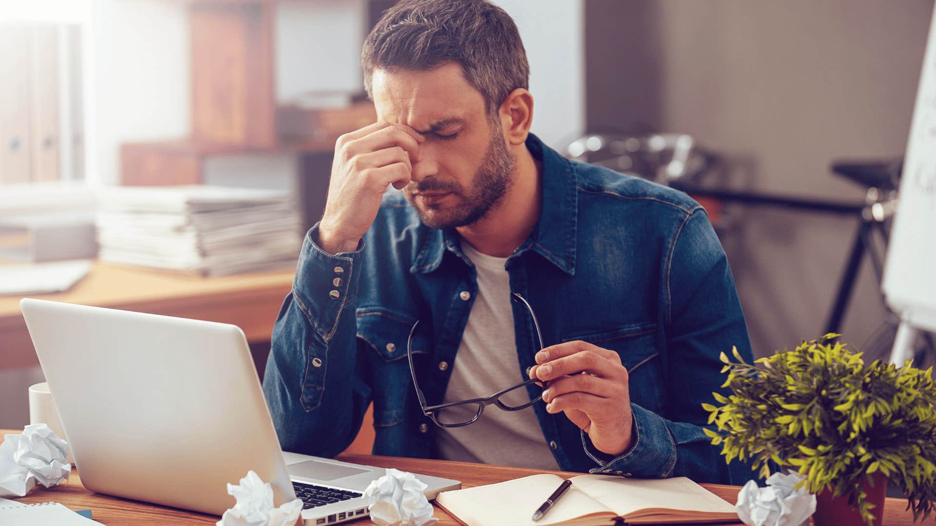 man taking off glasses looking stressed