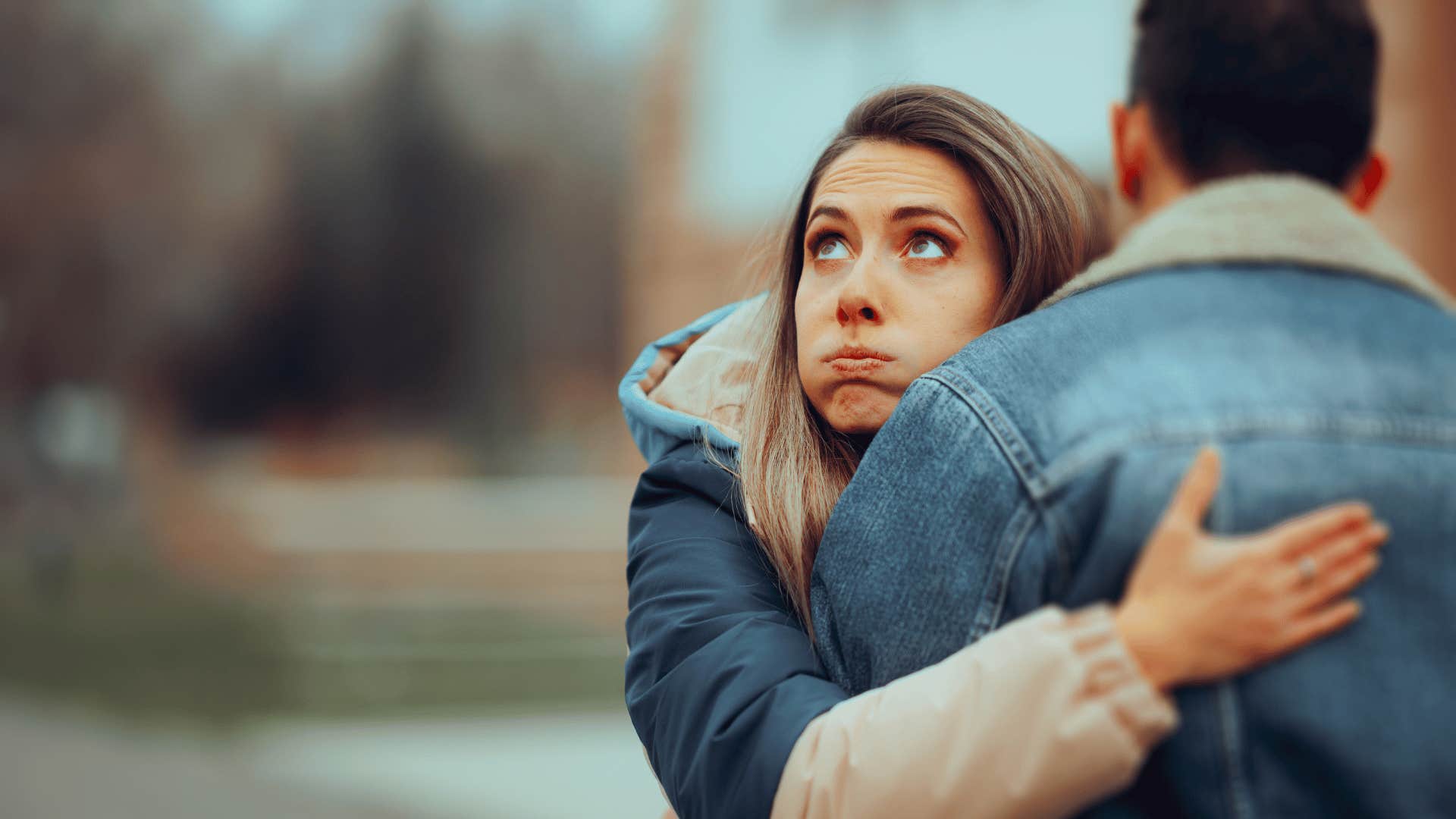 woman rolling her eyes while hugging a man