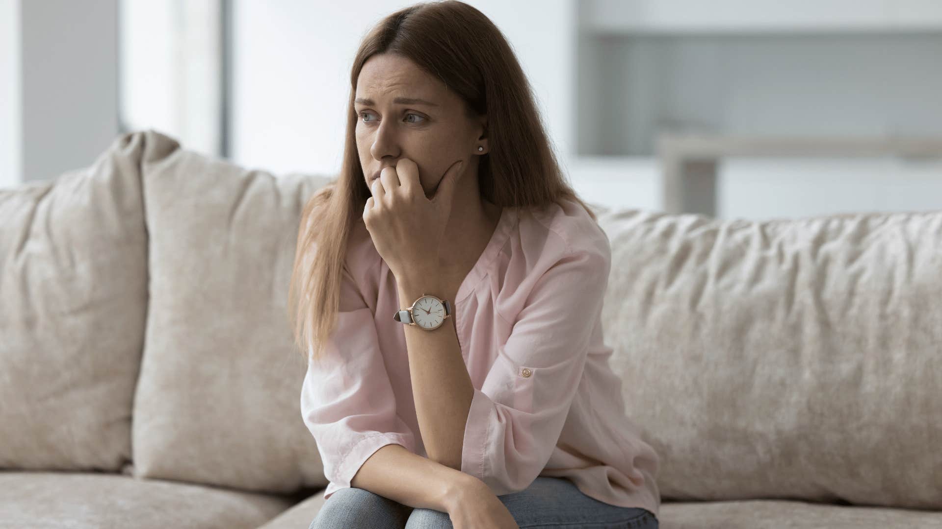 woman sitting on couch looking upset