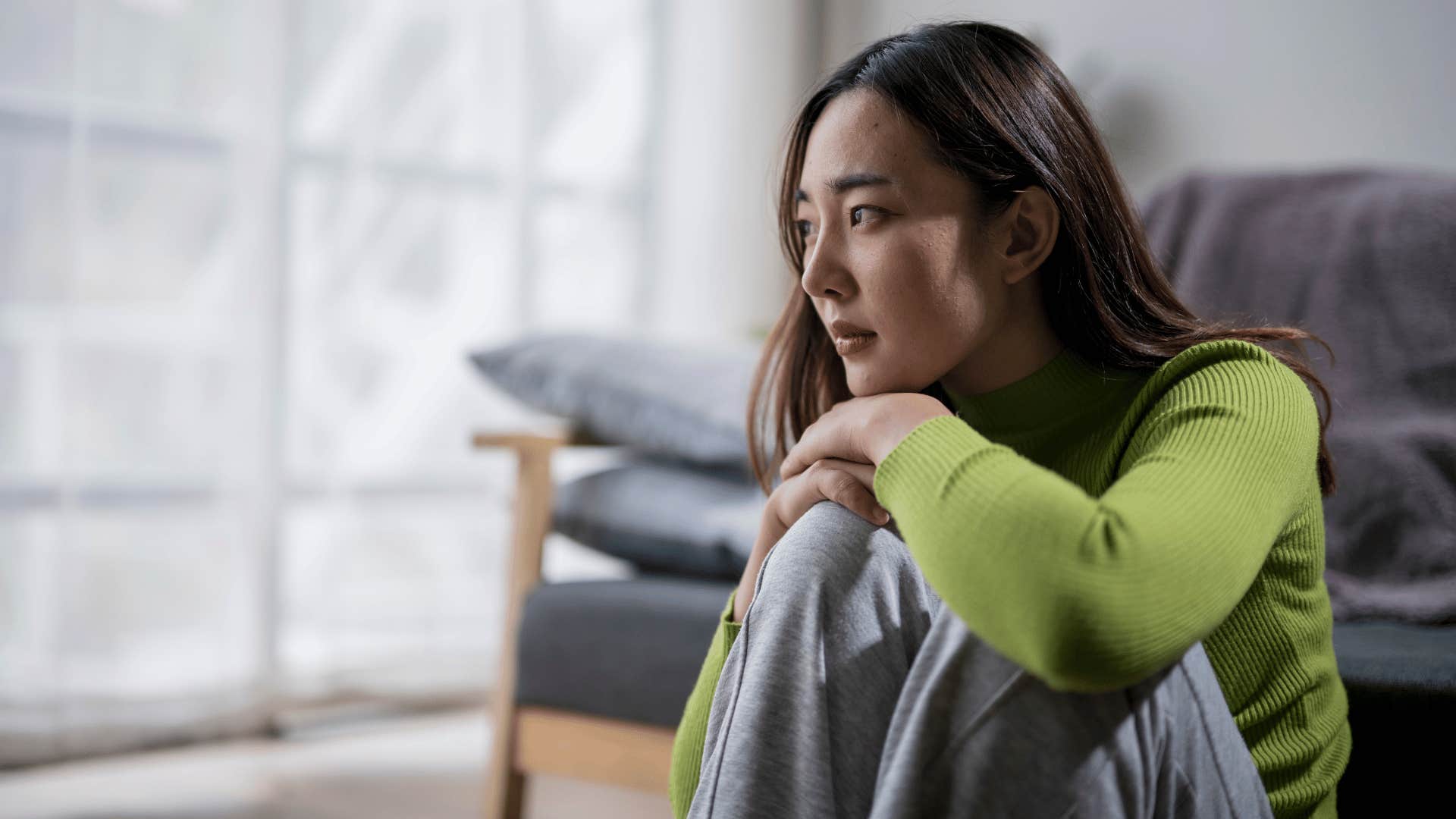 woman sitting alone on floor looking upset 