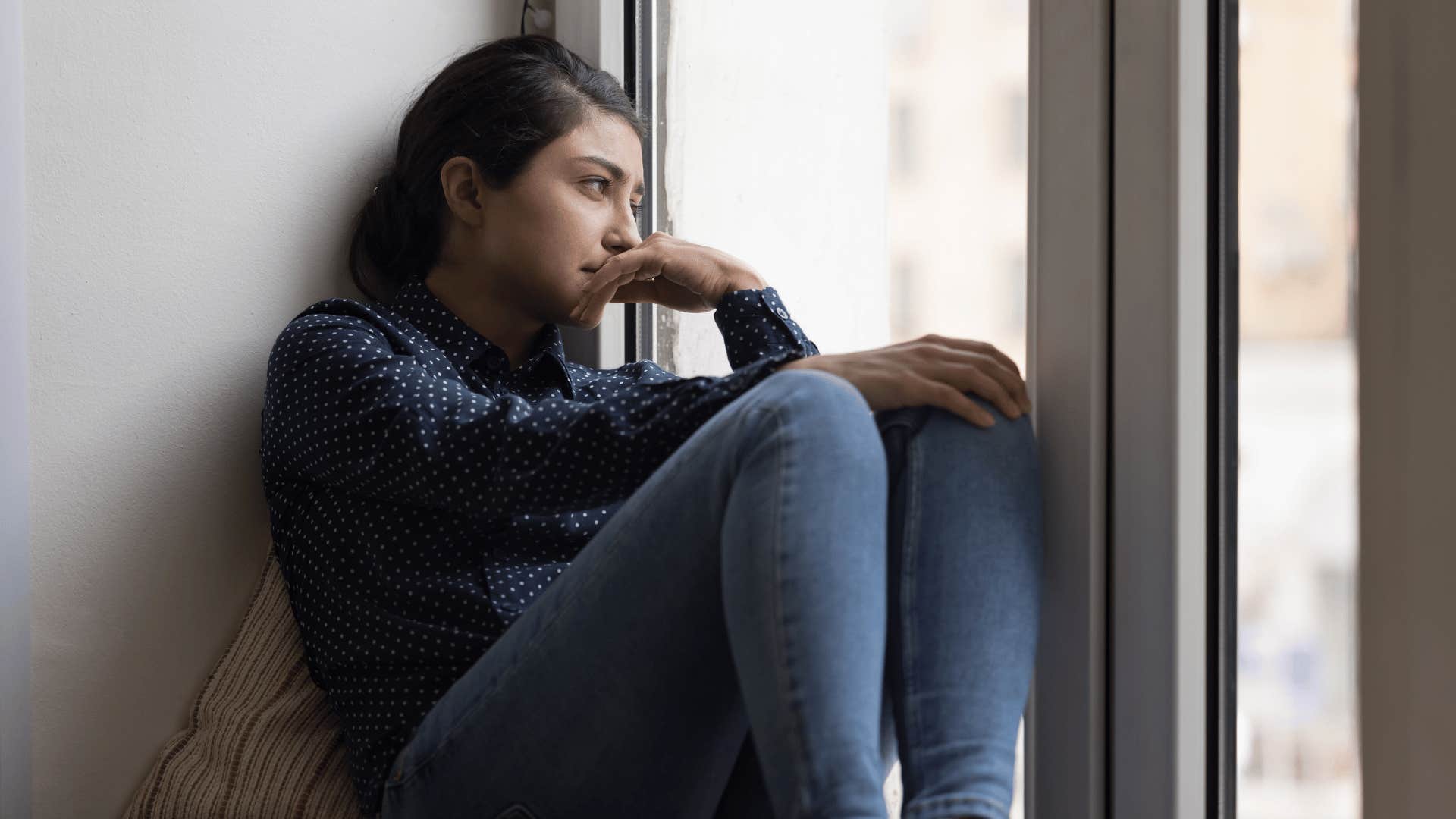 lonely woman looking out a window