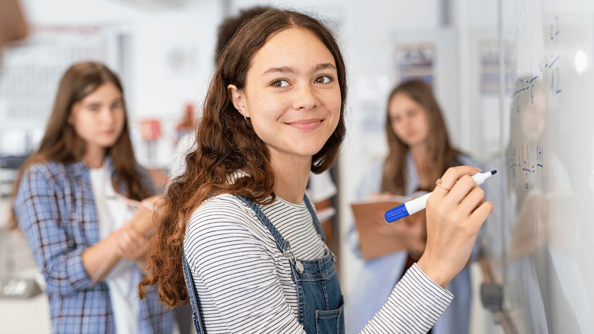 young woman writing on whiteboard 