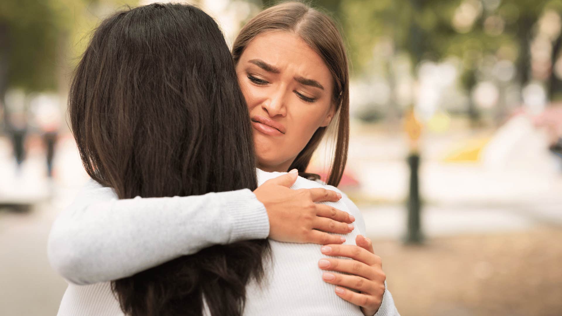 woman giving a disgusted look while hugging woman