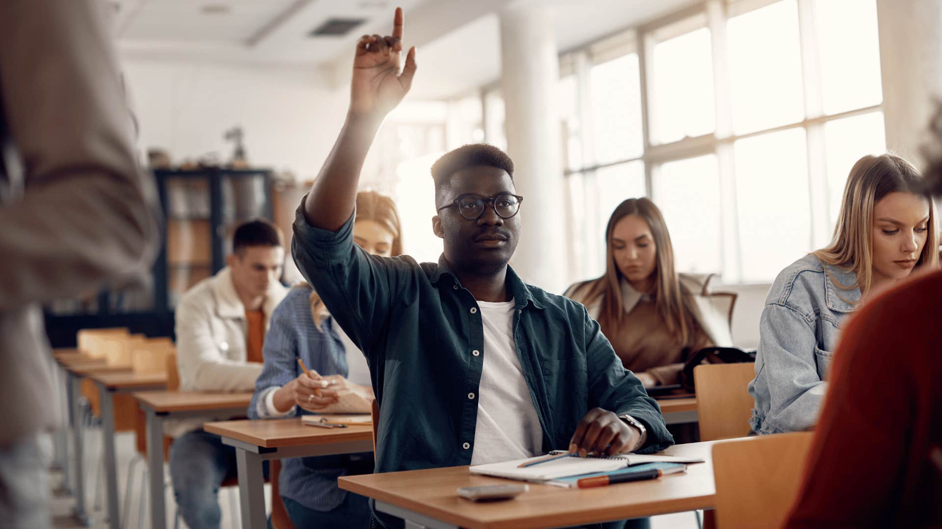 man raising hand in class