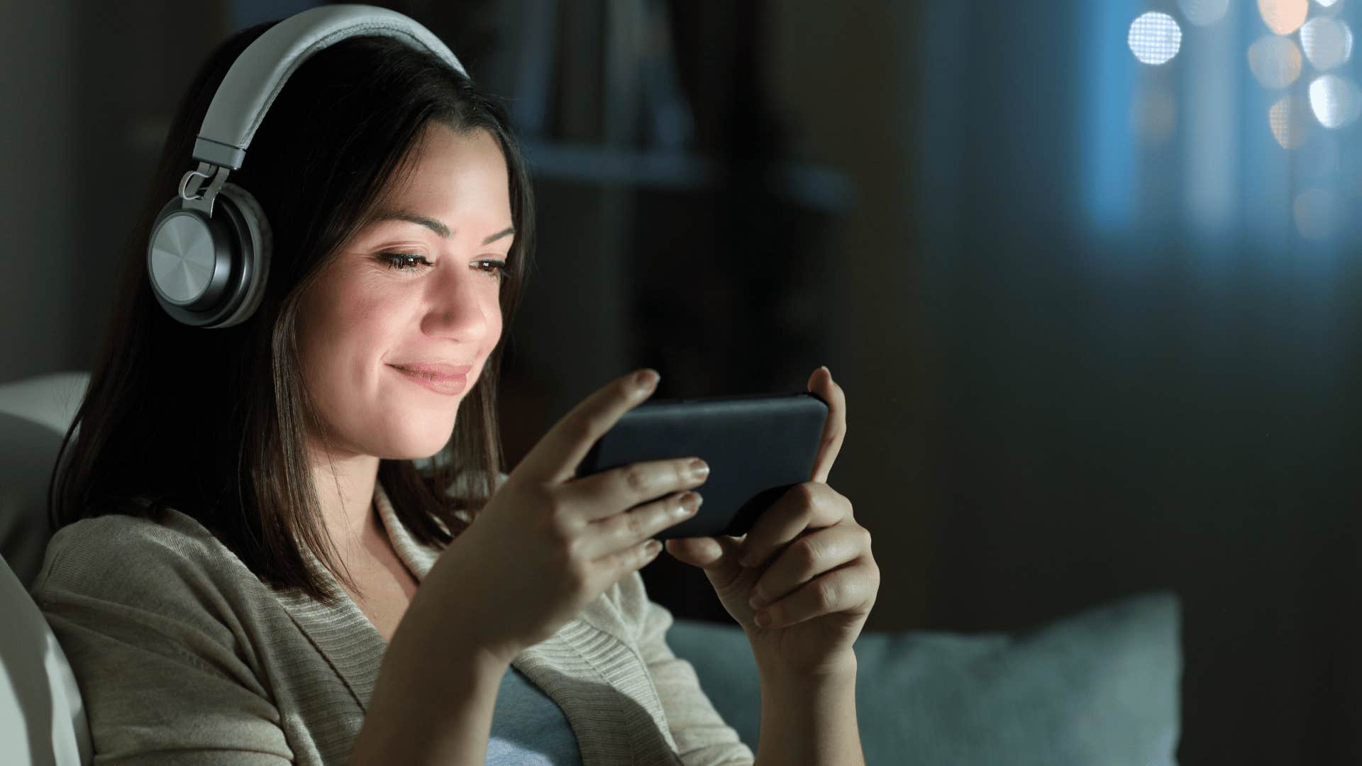 woman looking at videos late at night with headphones in 