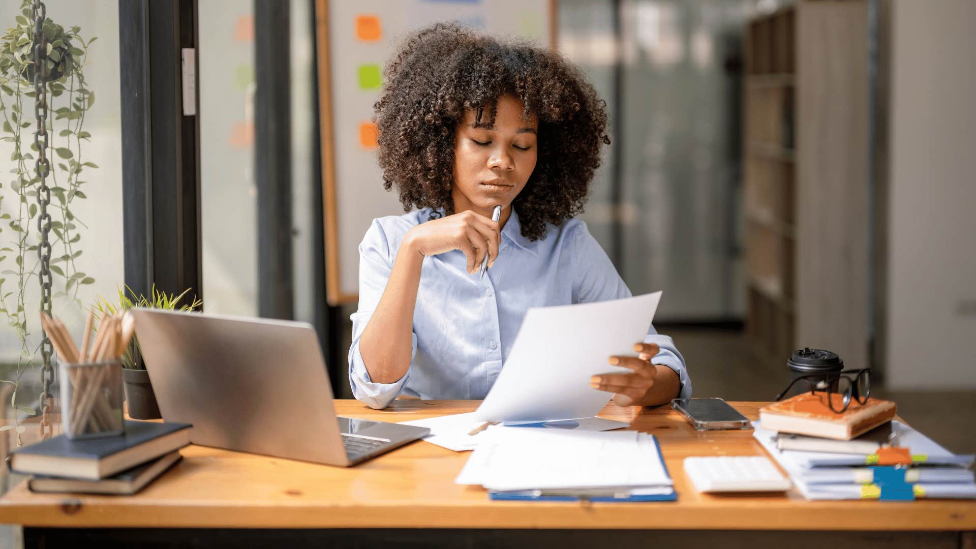 woman closing her eyes while holding paperwork