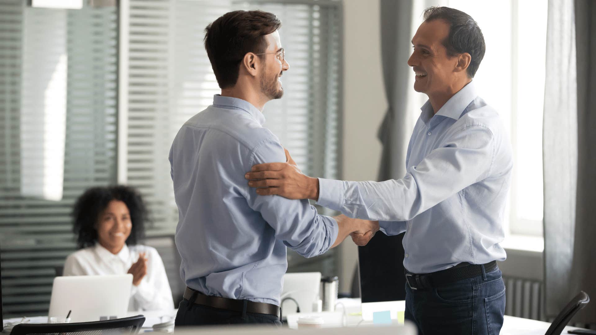 man patting other man's arm while handshaking 