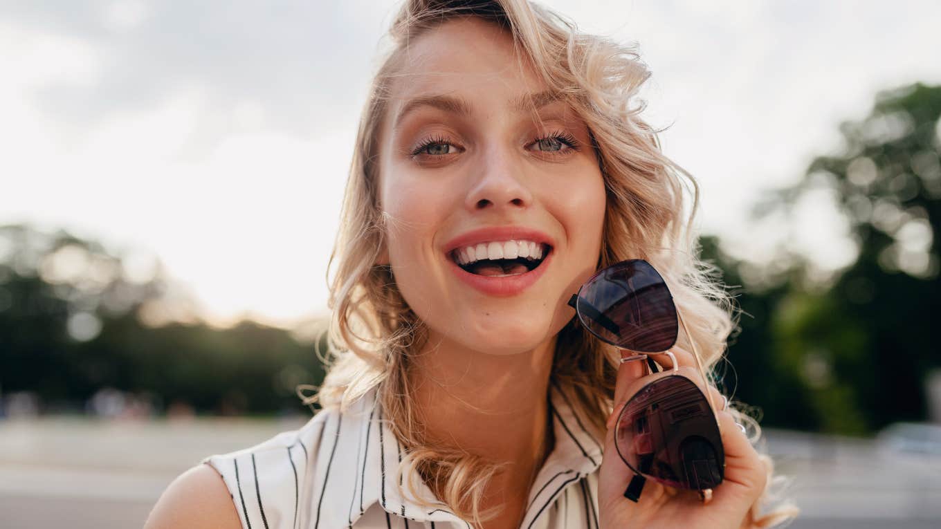 smiling woman holding sunglasses