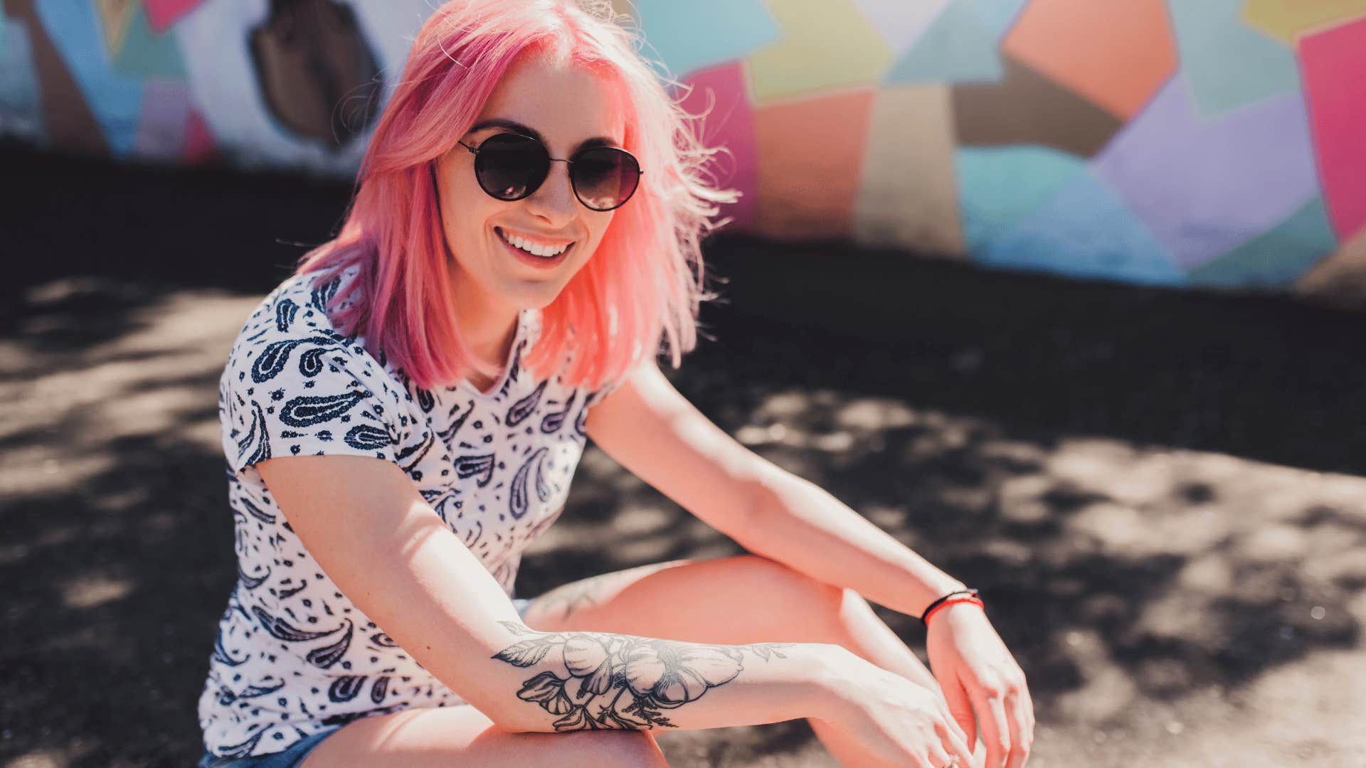 woman with pink hair sitting down and smiling