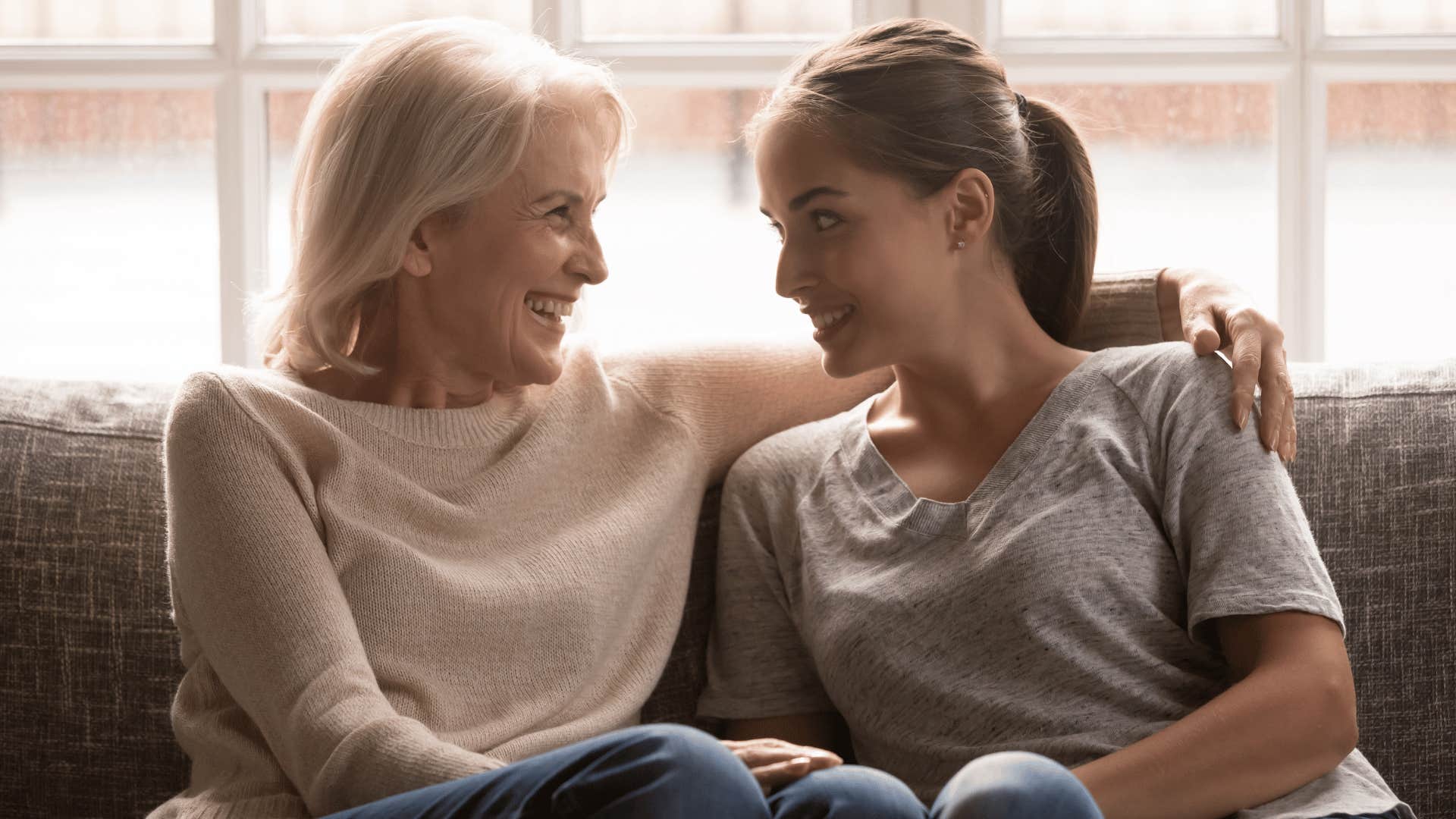 two women talking on the couch while older woman hugs younger women's shoulder