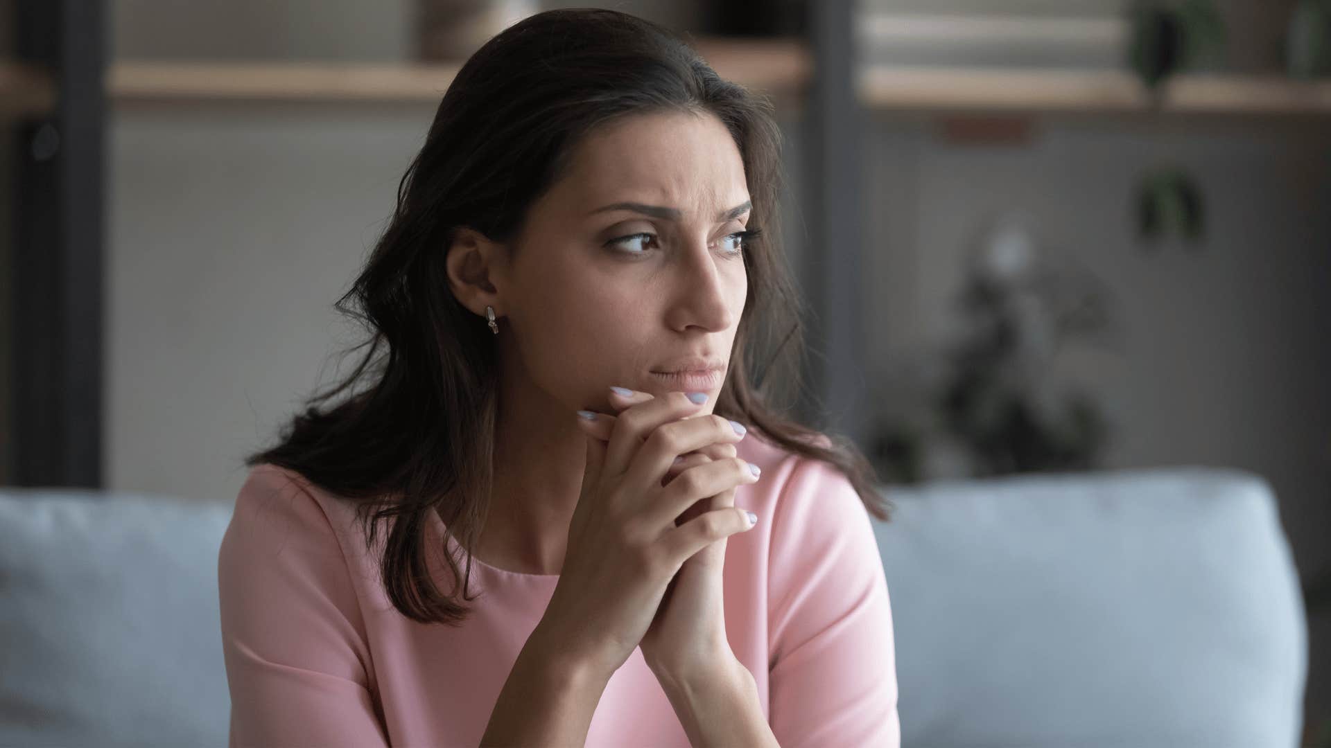 woman contemplating while sitting on couch