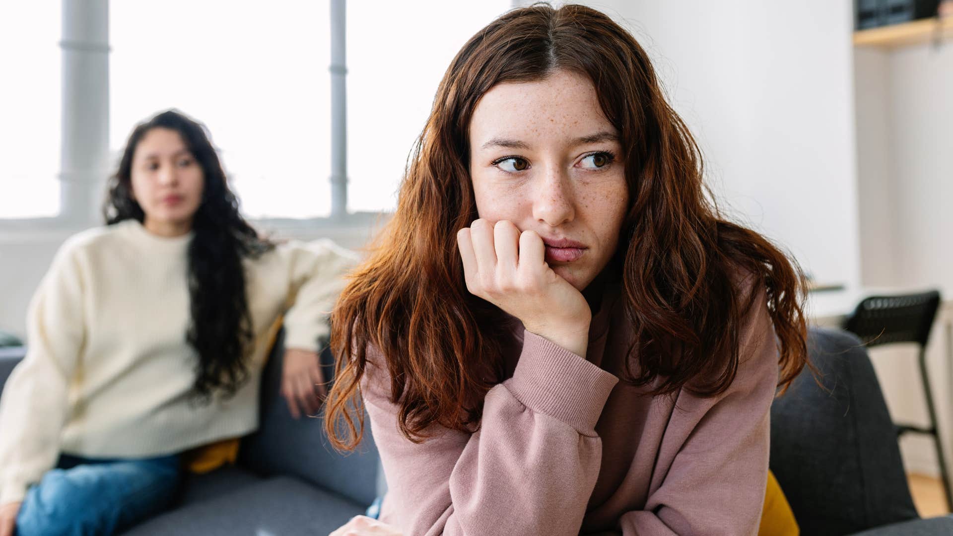 woman looking upset while friend is behind her 