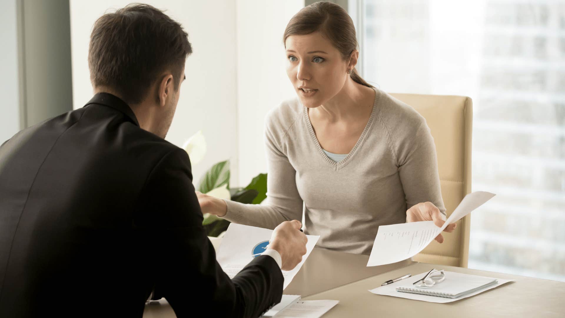 woman yelling at man while they sit at desk