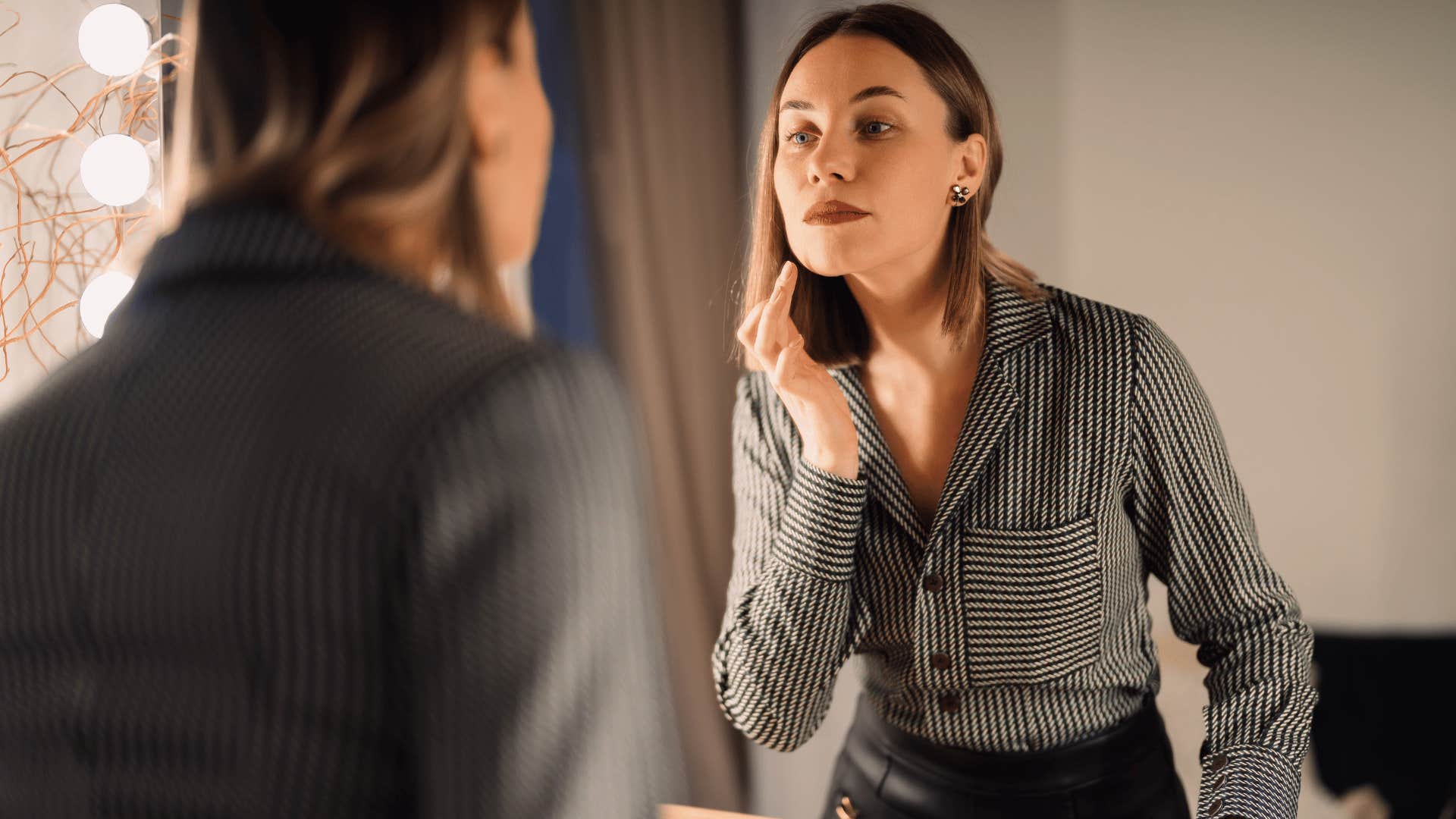 woman staring at herself in mirror