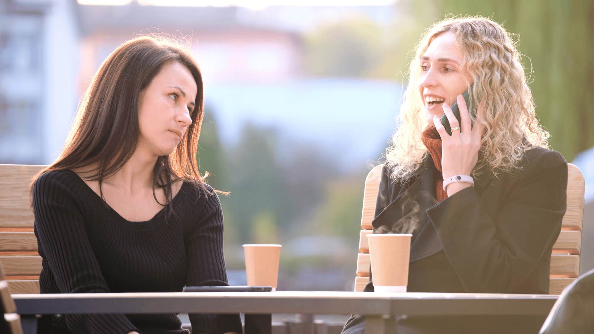 woman talking on the phone leaving other woman out 