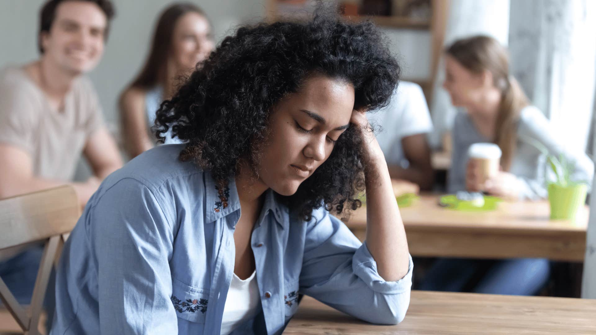 woman looking upset while people gossip about her