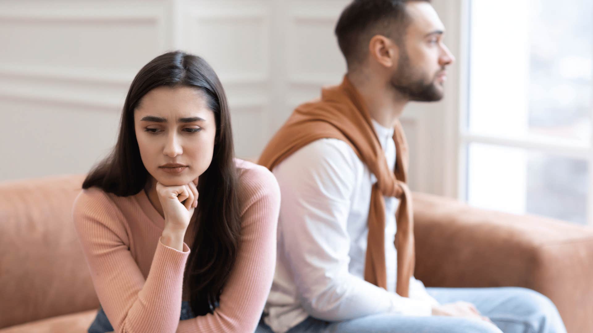 woman and man sitting on couch ignoring each other 