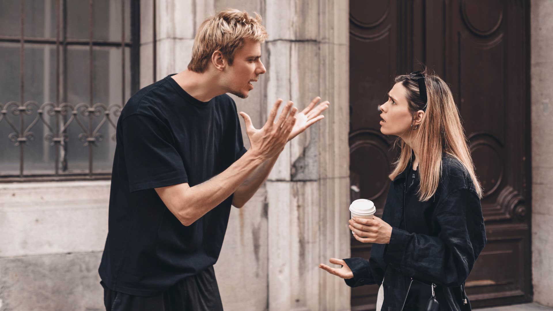 man and woman arguing outside building 