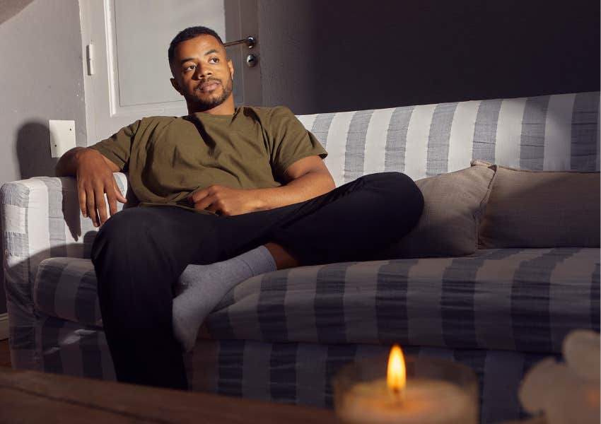 single man relaxes alone on couch at home with candle lit