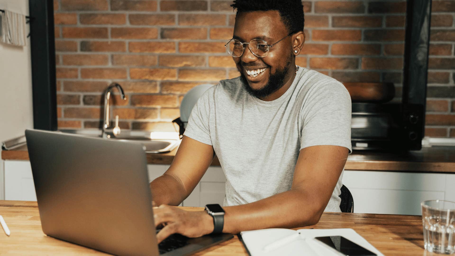 smiling man typing on a laptop