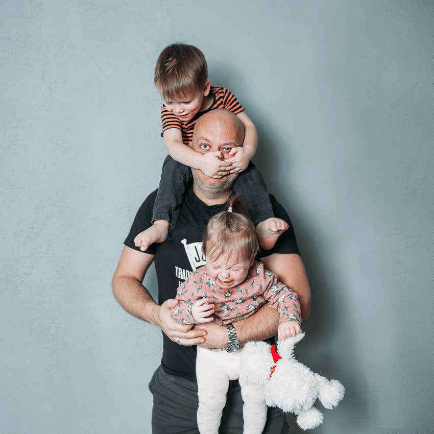 stressed man handling two young children