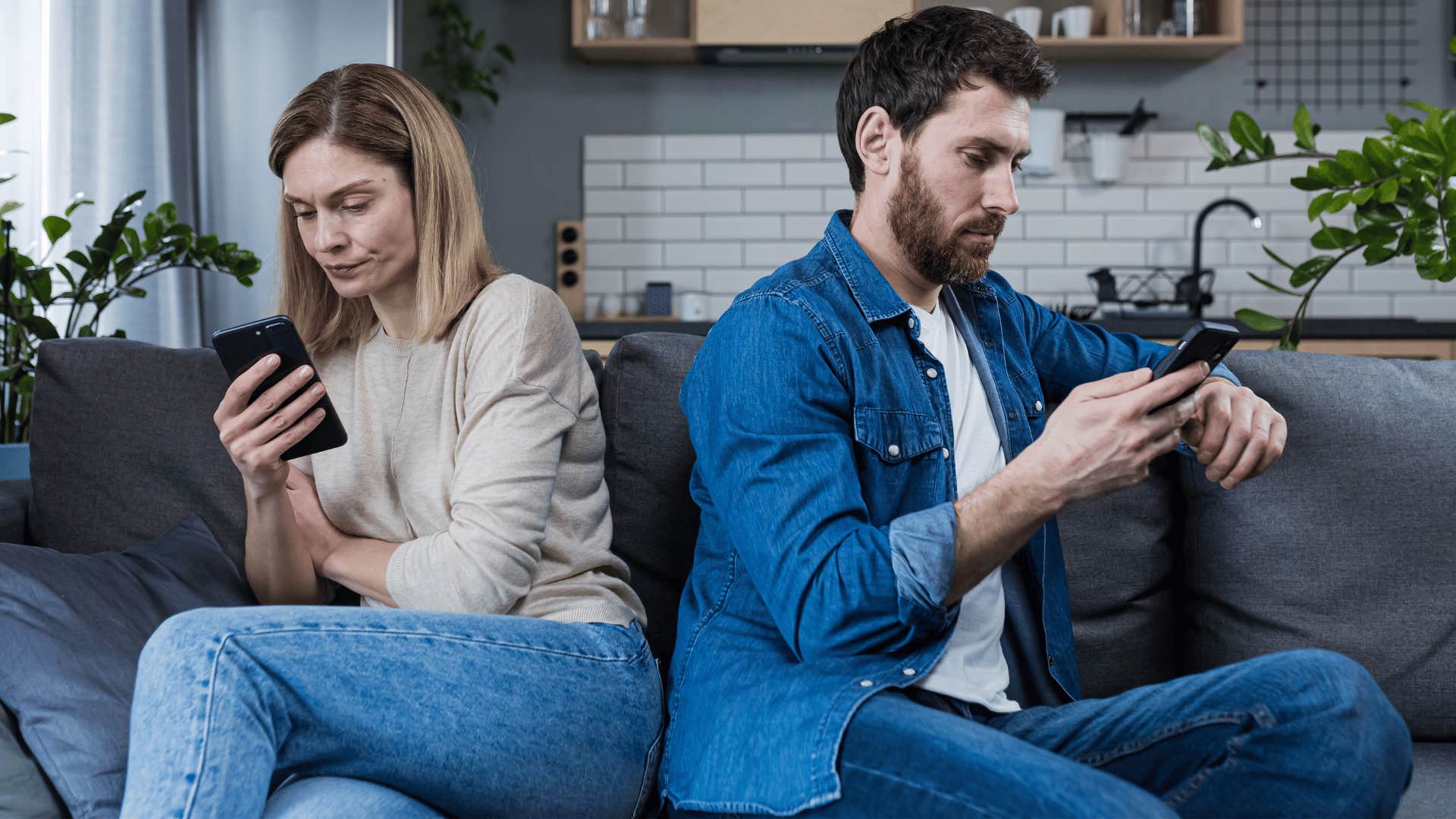 man and woman ignoring each other while scrolling through phones