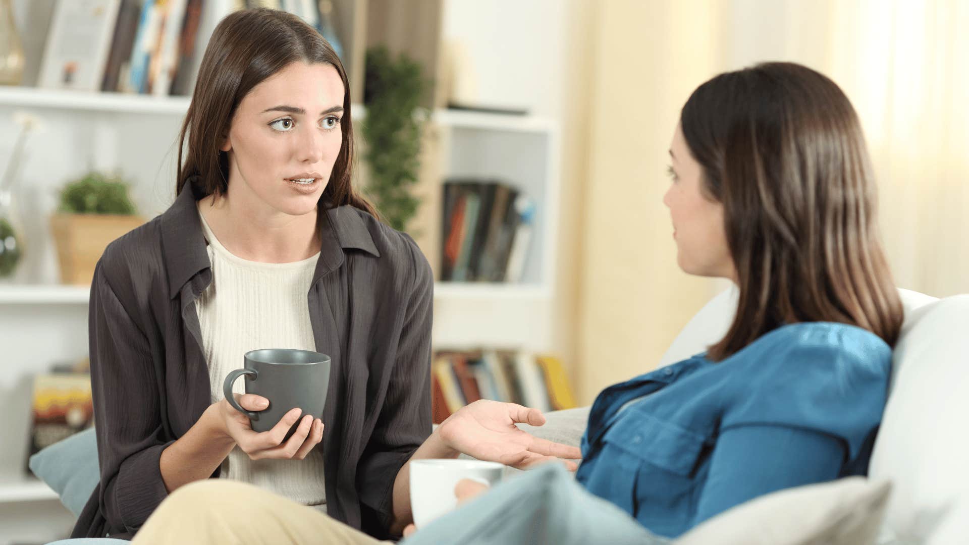 two women chatting on sofa while drinking coffee