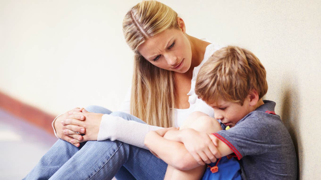 teacher sitting on ground talking to upset student