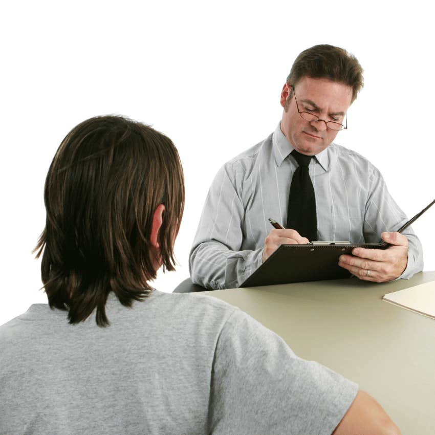 teenage boy talking to man in tie who is writing